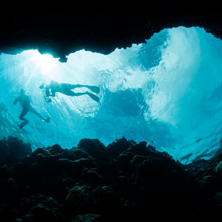 Divers silhouetted in cave