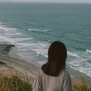 Woman overlooking beach, New Zealand.