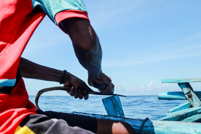 Fisherman on the edge of a boat sharpening a tool