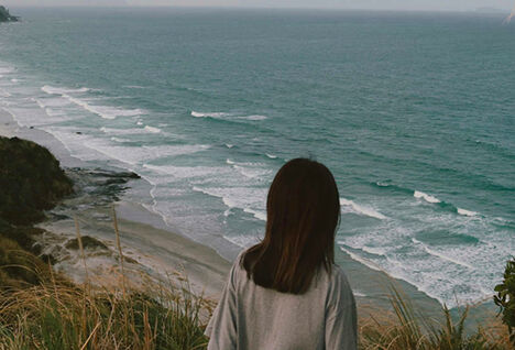 Woman overlooking beach, New Zealand.