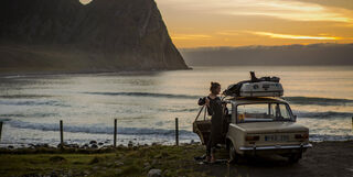 Man in a wetsuit standing by his car in Norway