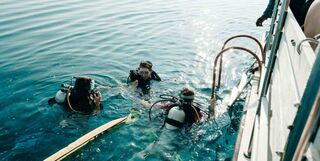 Three scuba divers at the surface.