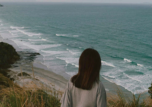 Woman overlooking beach, New Zealand.